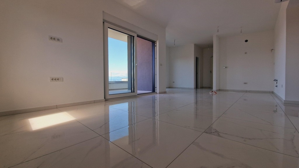 Otevřený obývací prostor s velkými okny a světlými dlaždicemi