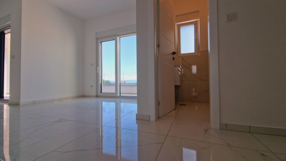 Obývací pokoj s přístupem do malé koupelny a výhledem na moře