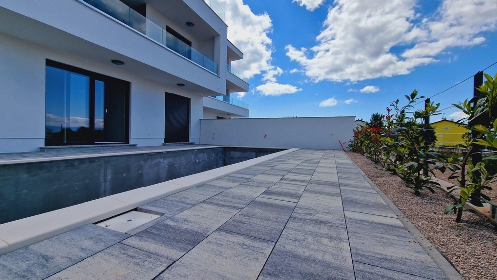 Exteriér moderní budovy s nedokončeným bazénem a zahradami