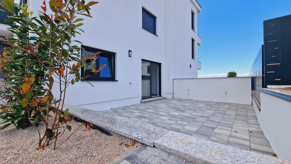 Venkovní plocha přízemního bytu s dlážděnou terasou a rostlinami