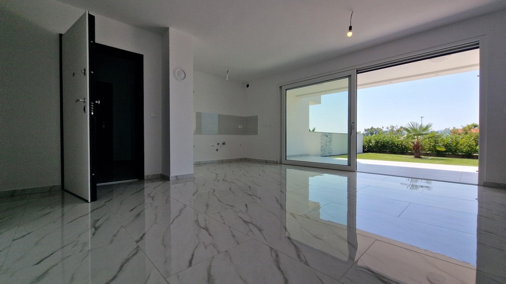 Otevřený obývací prostor s velkými okny vedoucími na terasu.