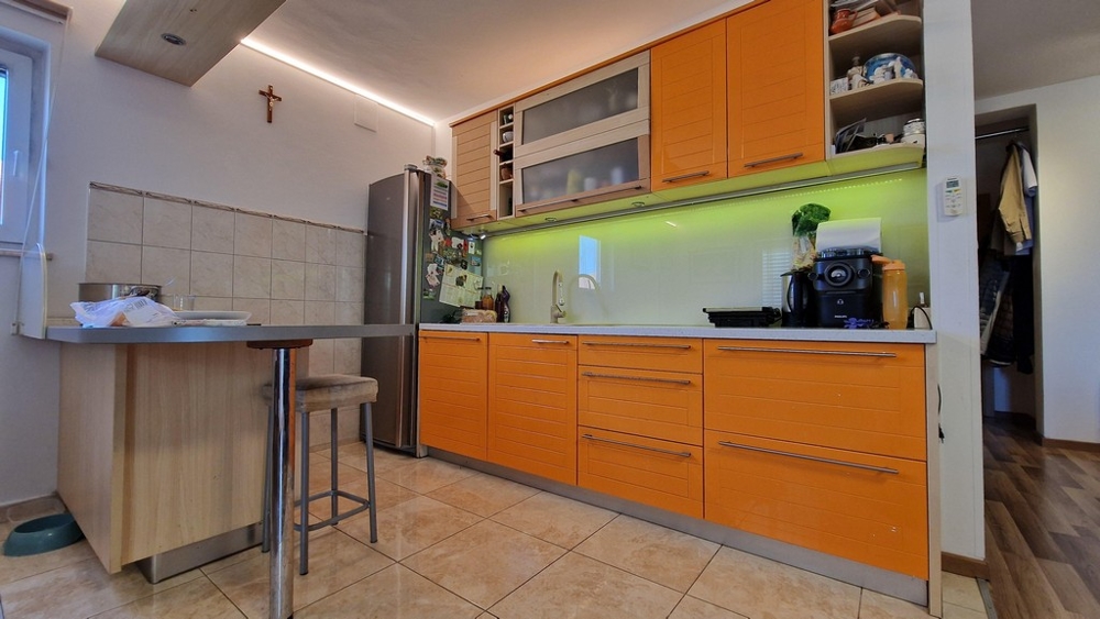 Moderní kuchyně s oranžovými čely a jídelním koutem