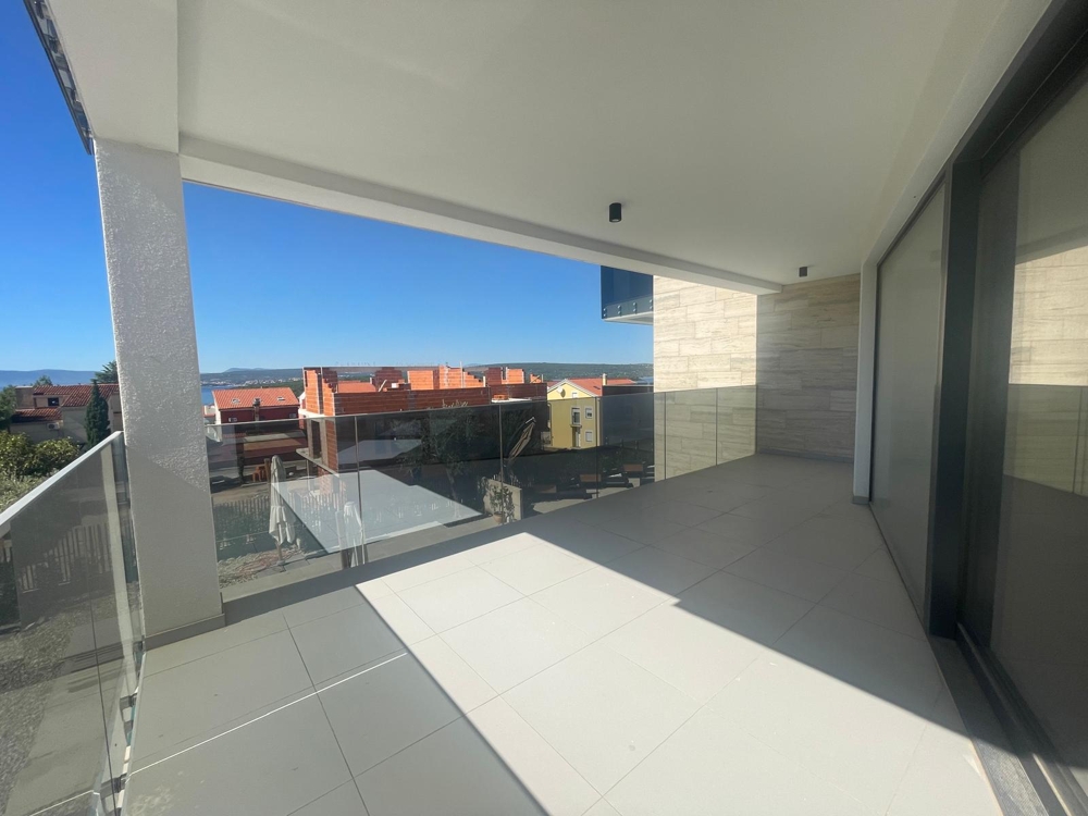 Velká terasa s velkými prosklenými dveřmi a výhledem na moře, dlážděná podlaha, částečně dokončený stav