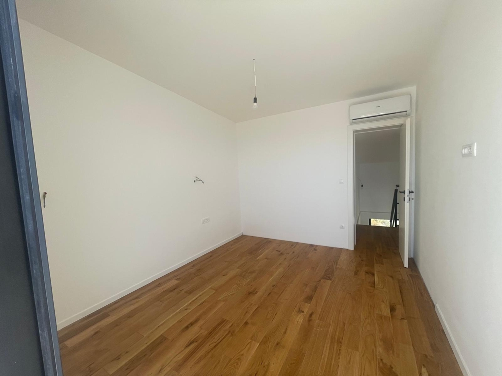 Interiér se třemi úzkými okny uspořádanými nad sebou, výhled do zeleně