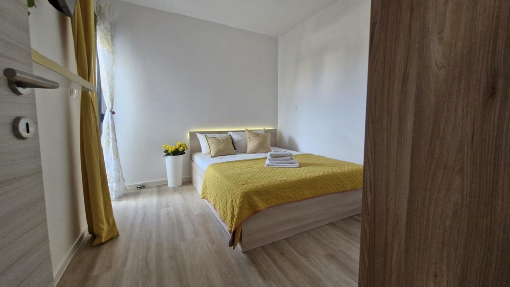 Ložnice s manželskou postelí, žlutou peřinou a dekoracemi