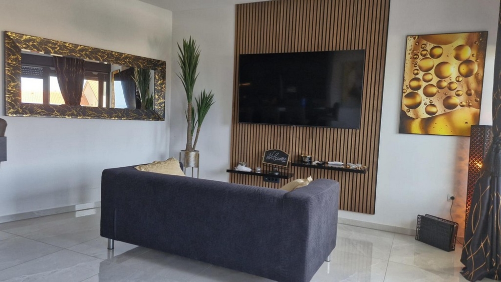 Obývací pokoj s velkou TV, pohovkou a dekorativními prvky