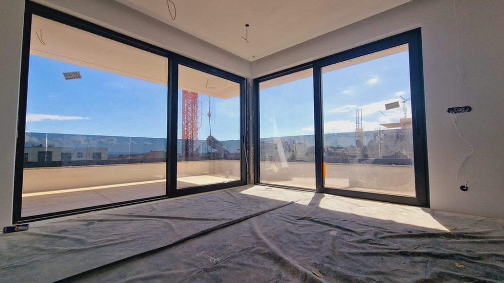 Obývací pokoj se dvěma velkými prosklenými čely, které propouštějí spoustu přirozeného světla a nabízejí výhled do okolí.