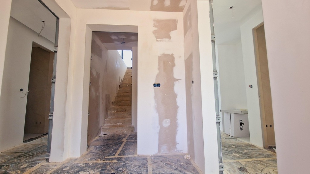 Schodiště a chodba ve výstavbě s viditelnými stěnami a otevřenými kabely.