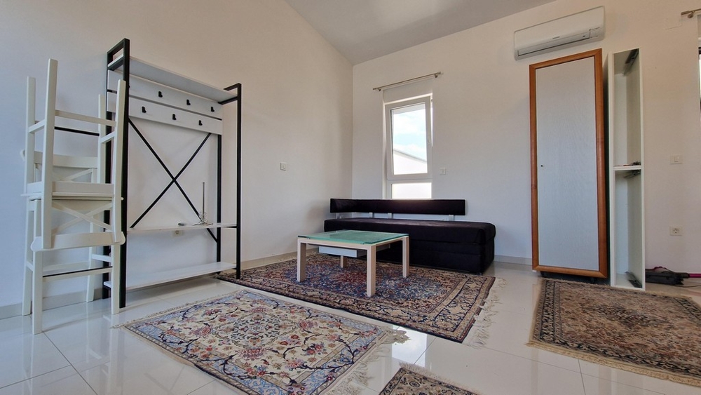 Obývací pokoj s pohovkou, koberci a klimatizací, moderní a světlý styl.