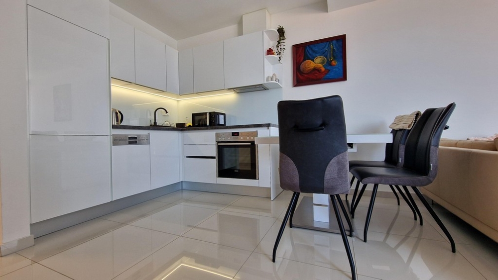 Prostorná, otevřená kuchyně s jídelním koutem a moderním vybavením včetně vestavěných spotřebičů.