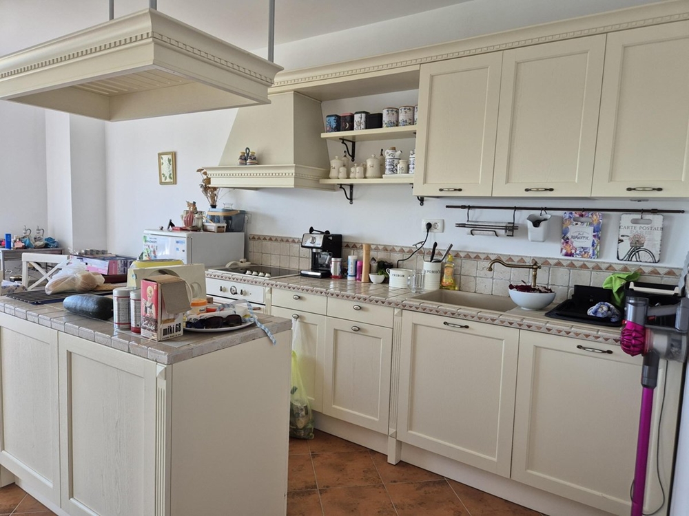 Další pohled na prostornou kuchyň se světlými skříňkami