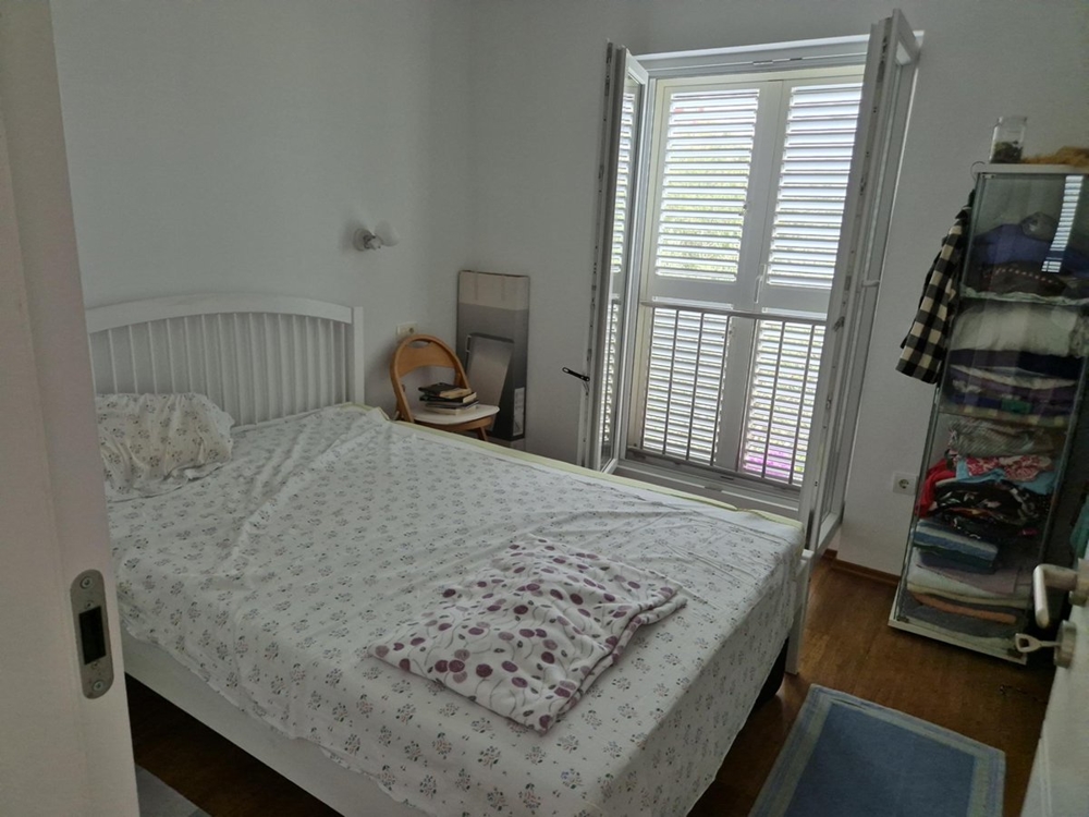 Ložnice s manželskou postelí, bílým nábytkem a oknem