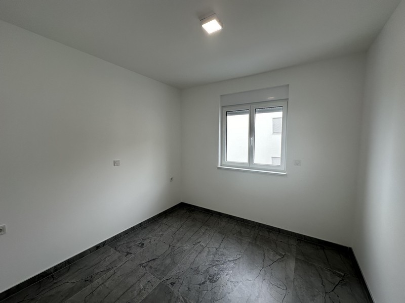 Prázdná ložnice s dlážděnými podlahami a oknem