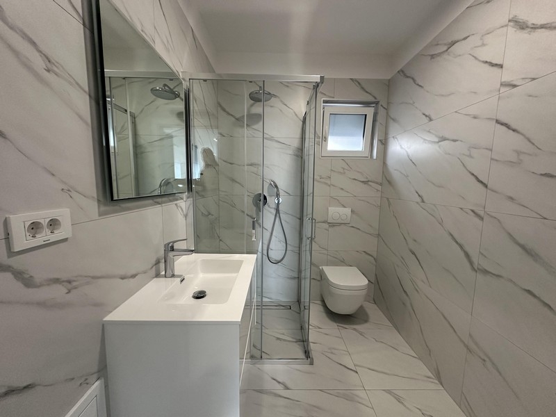 Moderní koupelna se sprchovým koutem, toaletou a umyvadlem