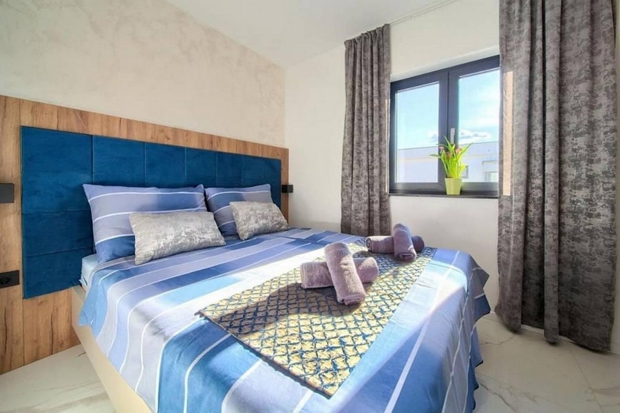 Moderní ložnice s velkou postelí a okny