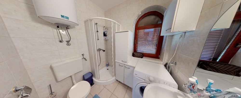 Světlá koupelna s oknem a sprchovým koutem.