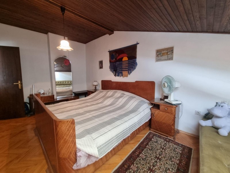 Ložnice s velkou postelí, dřevěným stropem a kobercem.