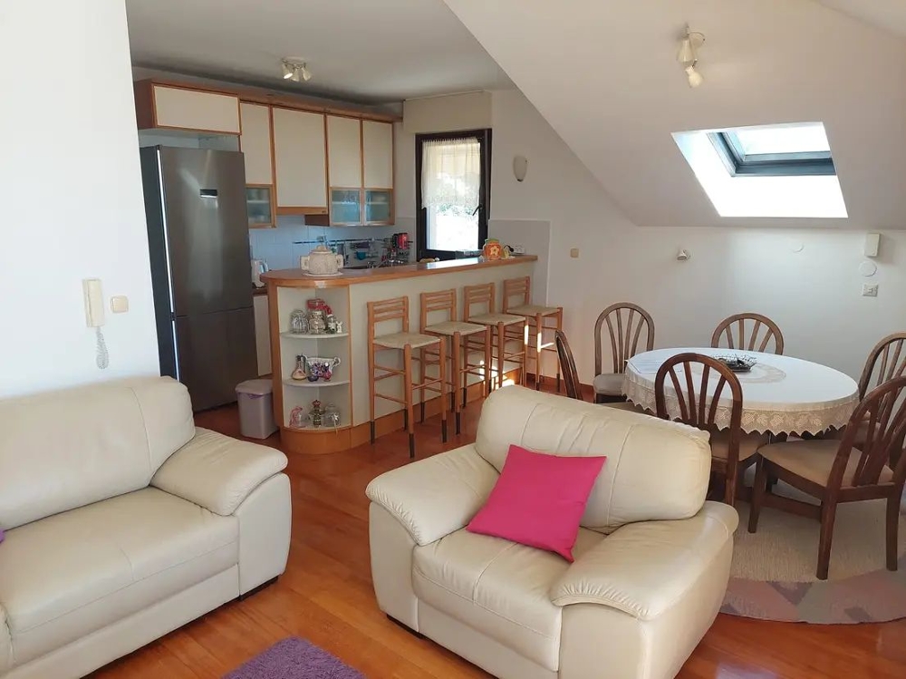 Útulný obývací pokoj s kuchyní, barem a jídelním stolem v podkrovním bytě