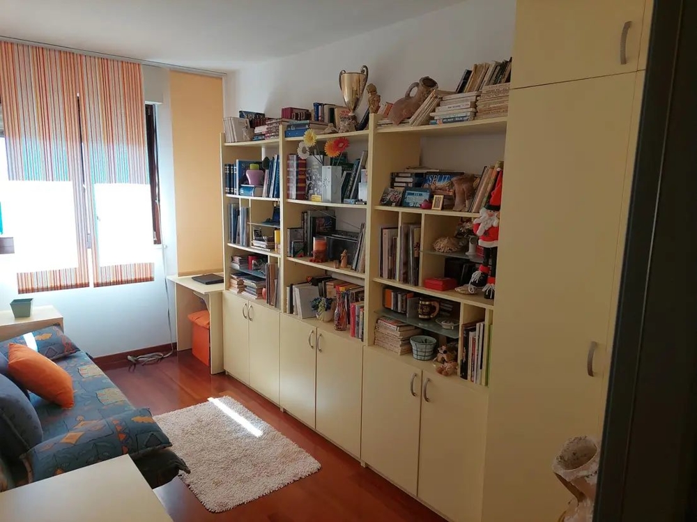 Pokoj s poličkami, stolem a pohovkou, světlá okna