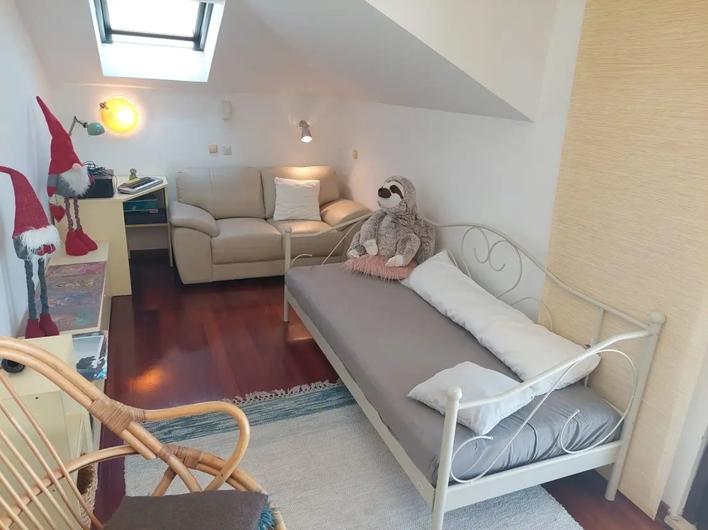 Pokoj s postelí, pohovkou, střešním oknem a dekoracemi včetně plyšáků