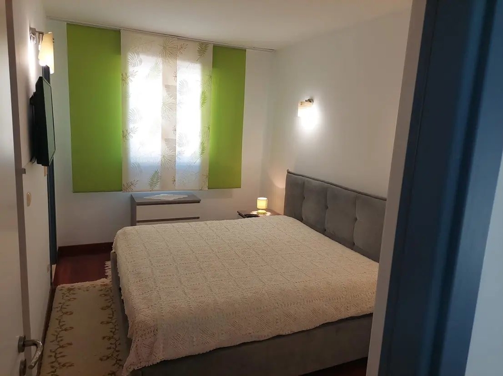 Ložnice s velkou postelí a zelenými závěsy