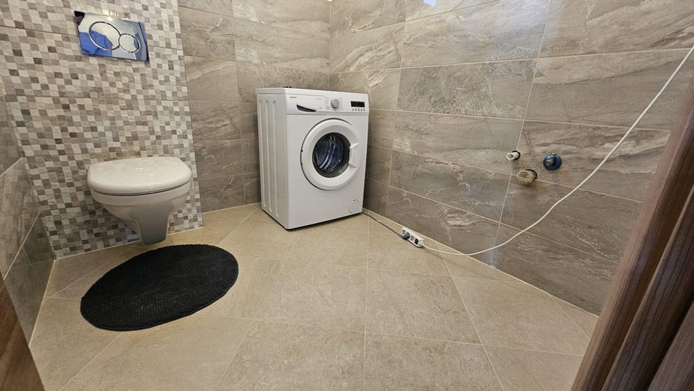 Koupelna s pračkou, WC a obklady stěn.