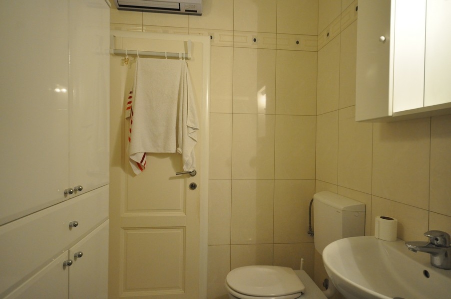 Koupelna s WC, umyvadlo, věšák na ručníky na dveře, světlá dlažba, moderní vybavení