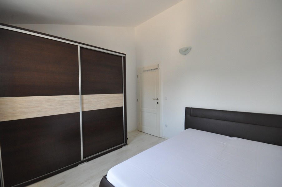 Ložnice s tmavou skříní a velkou postelí