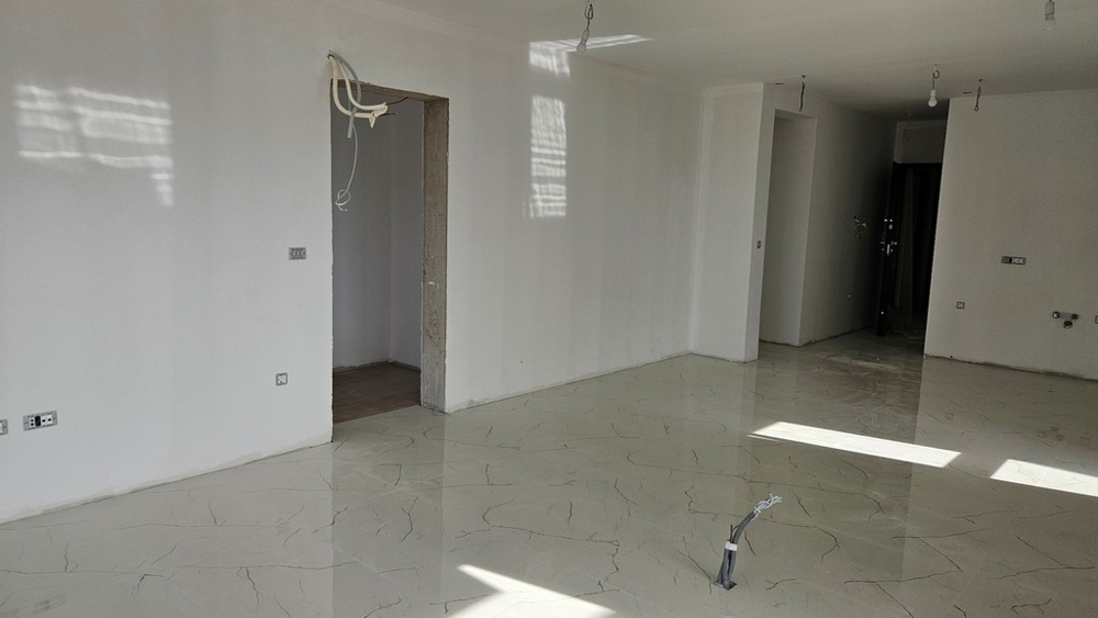 Nedokončený pokoj se světlou dlažbou, připravený na další vnitřní práce