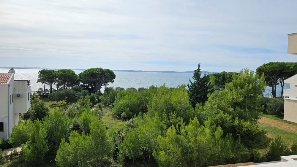 Výhled na moře z druhého patra obklopeného zelení a stromy