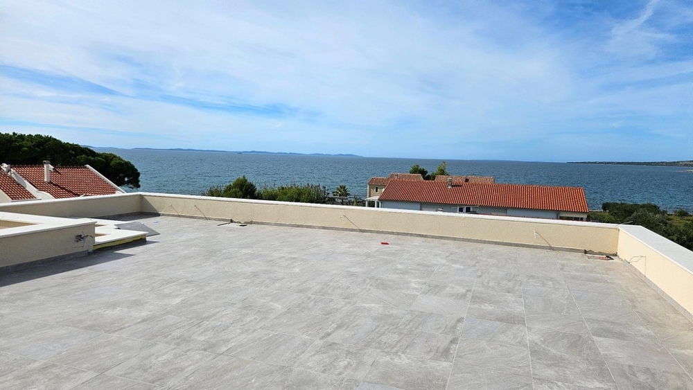 Střešní terasa s panoramatickým výhledem na moře a červené střechy domů pod nimi