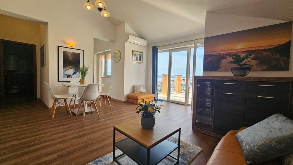 Obývací část s jídelním koutem a vstupem na terasu, zdobená rostlinami a nástěnnými malbami