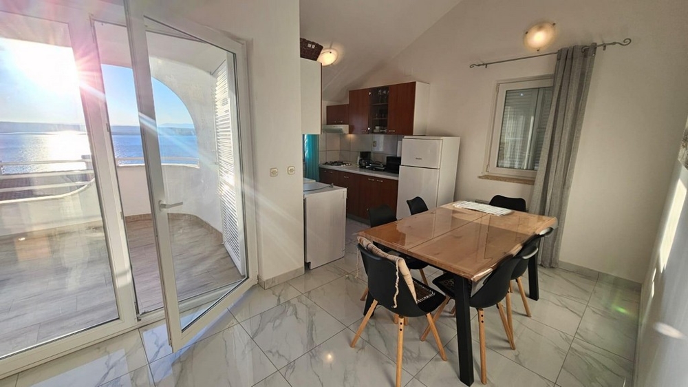 Výhled na terasu, jídelní stůl a kuchyňský kout.