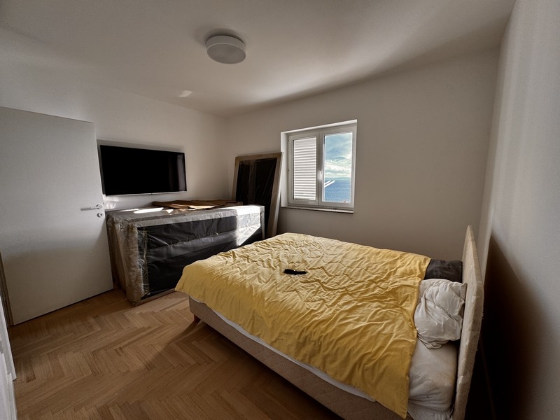 Ložnice s čalouněnou postelí, žebříkem a otevřeným stěnovým prostorem