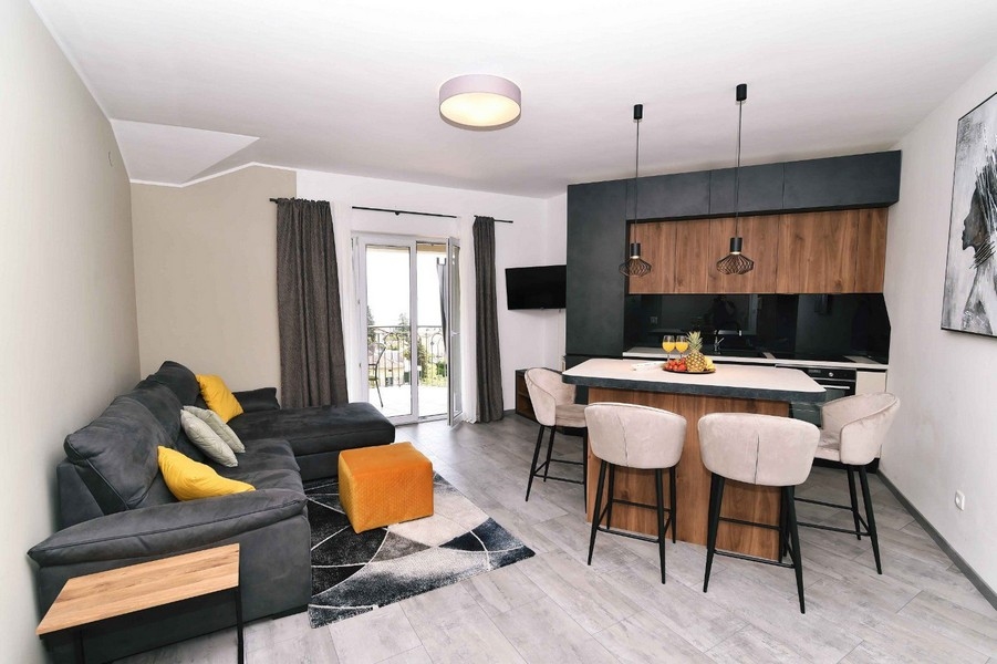 Světlý obývací pokoj s moderním nábytkem, přístupem na balkon a výhledem na moře v centrální poloze.