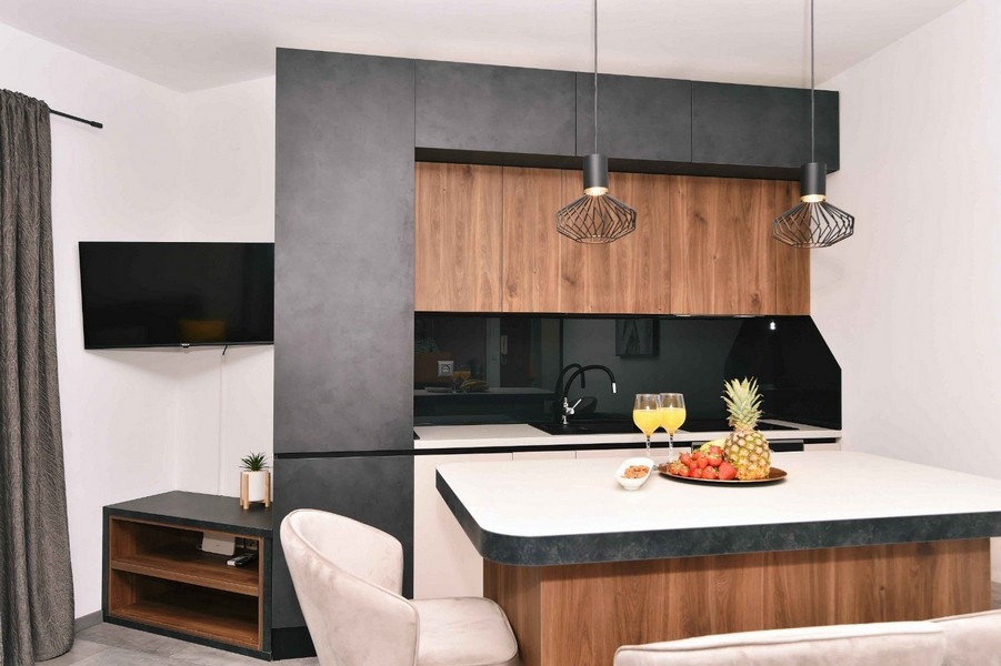 Stylová kuchyně s dřevěnými dvířky, moderním designem a prostornou pracovní plochou.