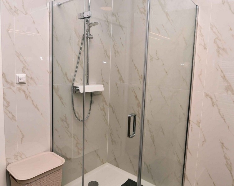 Sprchový kout s prosklenými dveřmi a moderní vodovodní baterií v kvalitním bytě.