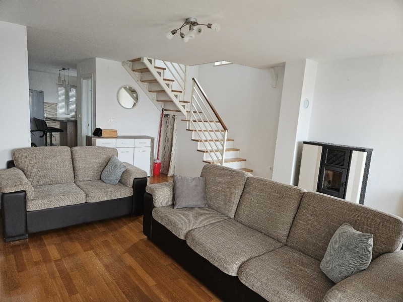 Obývací pokoj se sedací soupravou, schodištěm a peletovými kamny