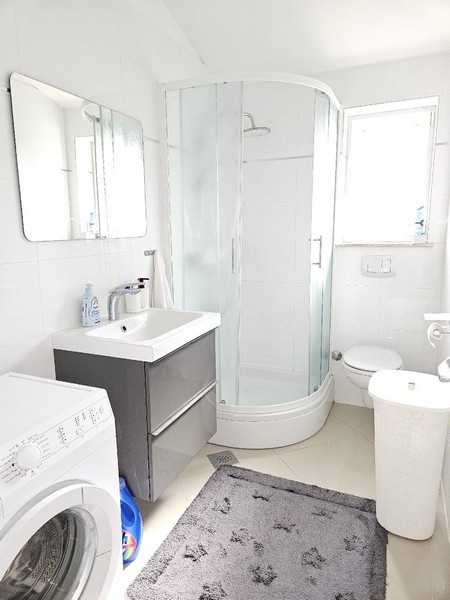 Světlá koupelna se sprchovým koutem.