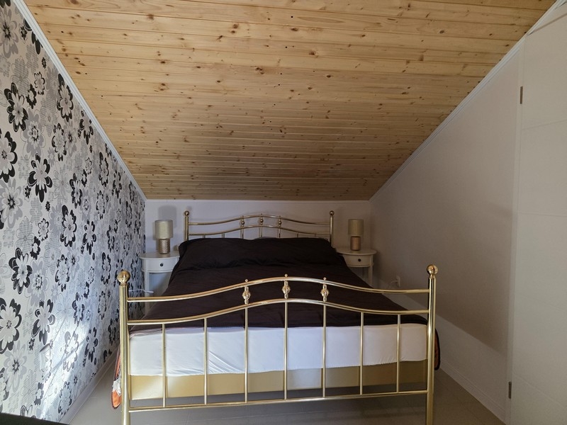 Ložnice v podkroví se zkoseným stropem a manželskou postelí