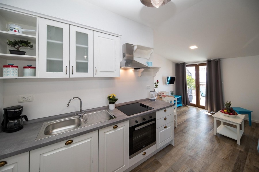 Moderní kuchyně s bílými skříňkami a šedou pracovní deskou