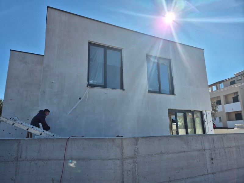 Vnější pohled na dům s velkými okny a slunečním světlem