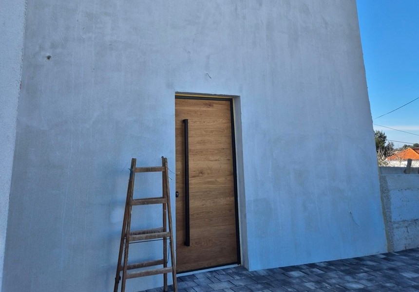 Moderní vchodové dveře s dřevěným vzhledem a žebříkem na fasádě