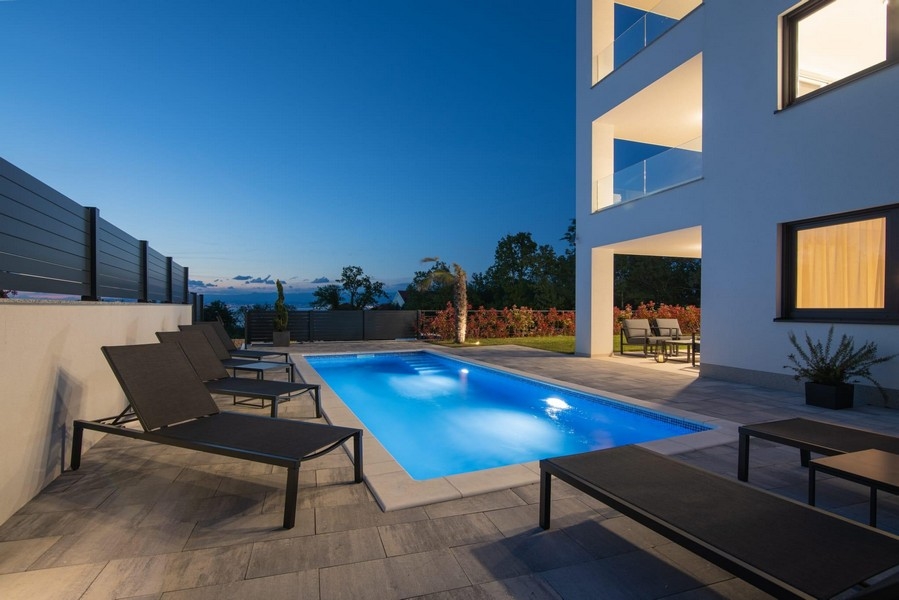 Noční záběr osvětleného bazénu s lehátky