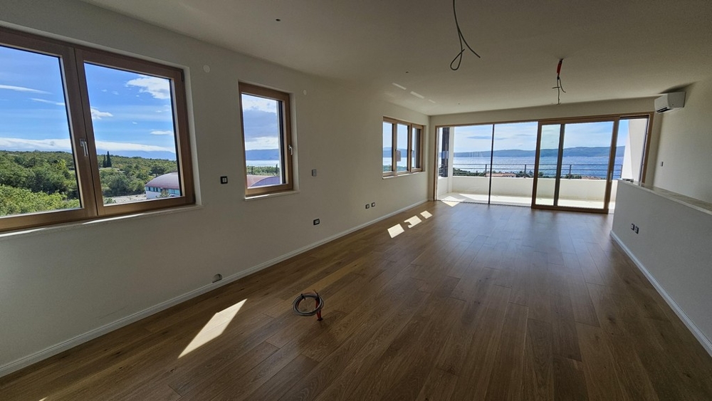 Prostorný obývací pokoj s výhledem na moře a okny od podlahy ke stropu