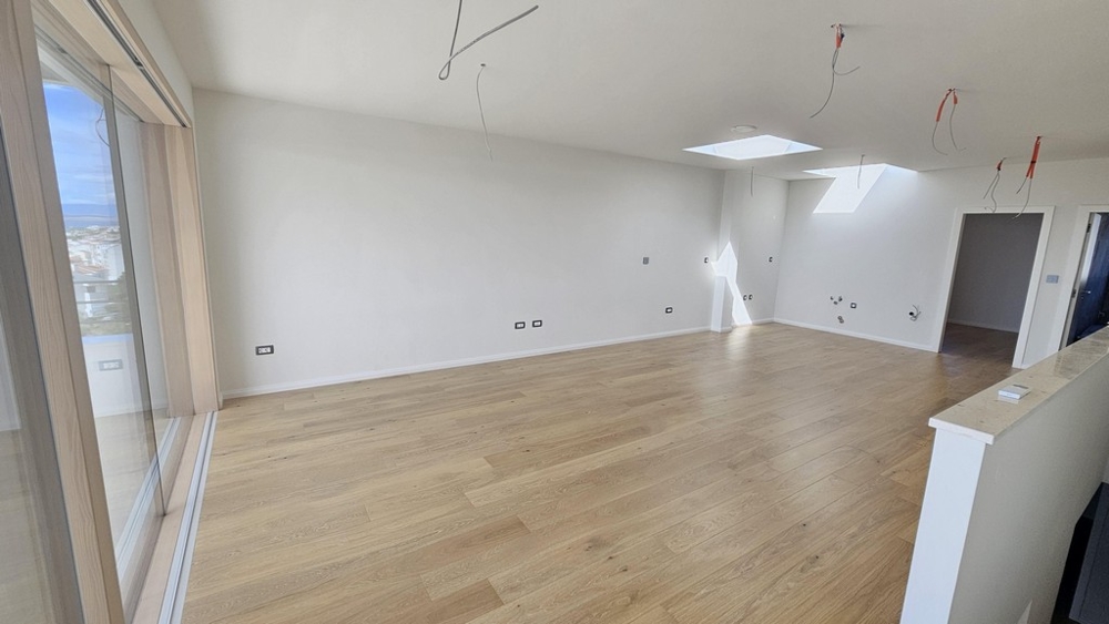 Otevřený obývací prostor s velkými okny a vstupem na balkon