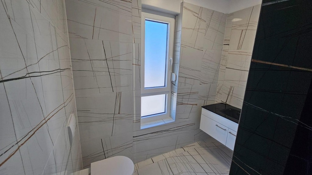 Koupelna s moderním dlaždicovým designem a oknem