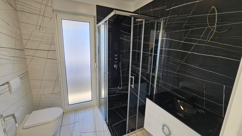 Stylová koupelna se sprchovým koutem a tmavými obklady