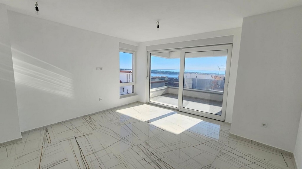 Prostorný obývací pokoj s panoramatickými okny a výhledem na moře