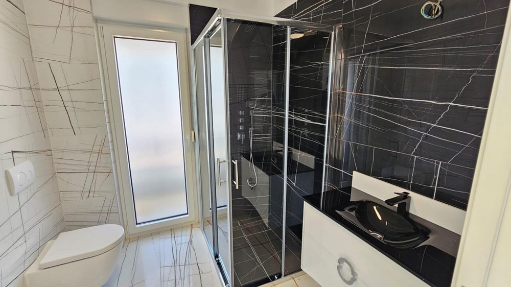 Elegantní koupelna s černým sprchovým koutem a umyvadlem